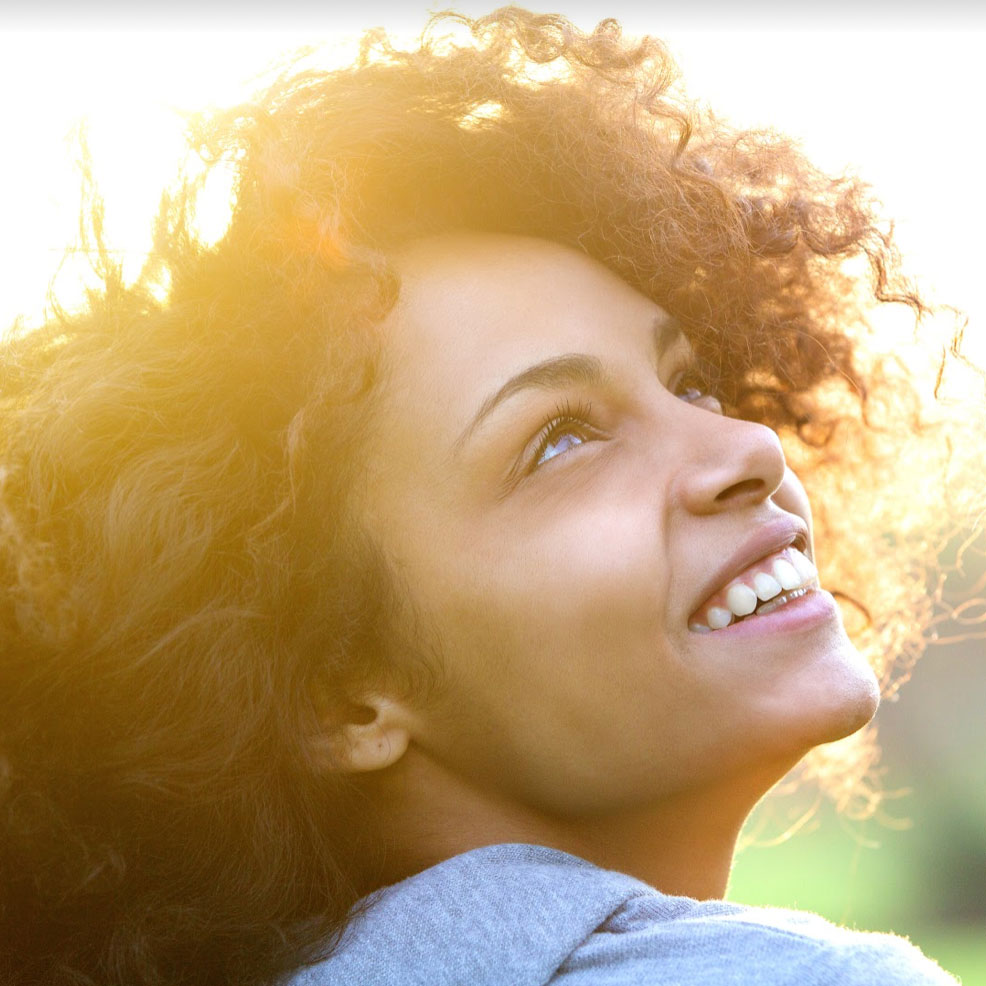 Woman's face smiling with sun behind hair