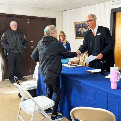 This is an image of a judge in a black robe shaking the hand of a woman.