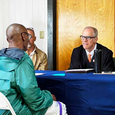 This is an image of a judge dressed in a black robe talking to a man during a court hearing.