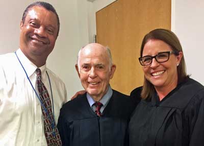 This is an image of two men and one woman dressed in a black robe.