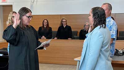 This is an image of a judge administering an oath to a woman with her right hand raised while another group of female judges look on.