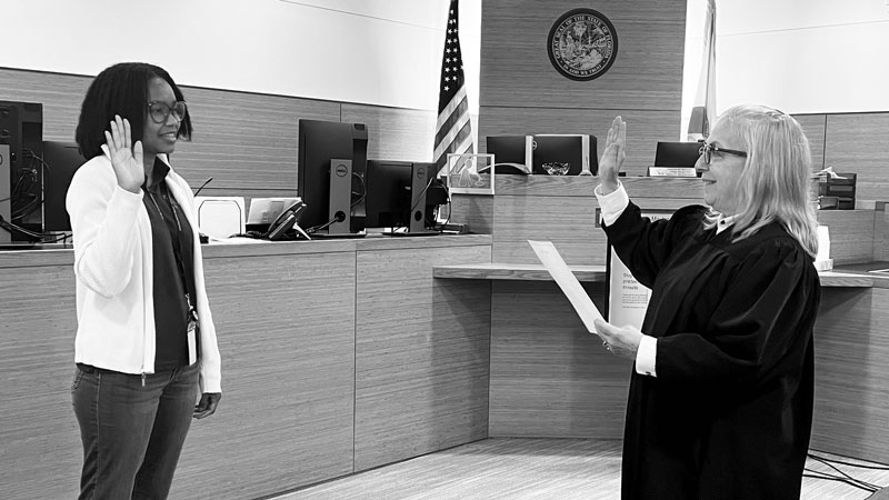 This is an image of a judge administering an oath to a woman with her right hand raised.