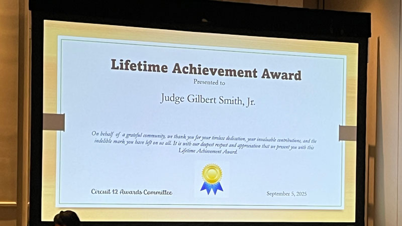 This is an image of a presentation screen in a large meeting that is displaying an award certificate for Judge Smith.