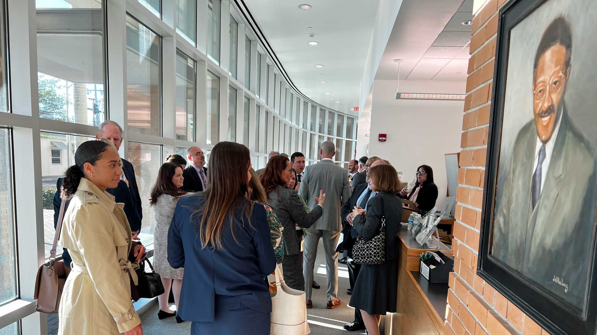 This is a photograph of people gathered in a space, talking and mingling over coffee and pastries.