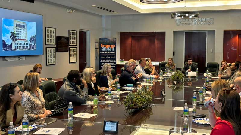 This is an image of a group of people sitting around a conference table having a conversation.