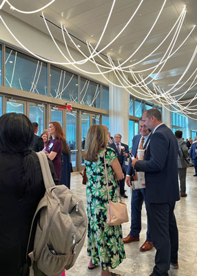 People are talking, eating pastries and drinking coffee in a lobby with rope-style lighting hanging from the ceiling.
