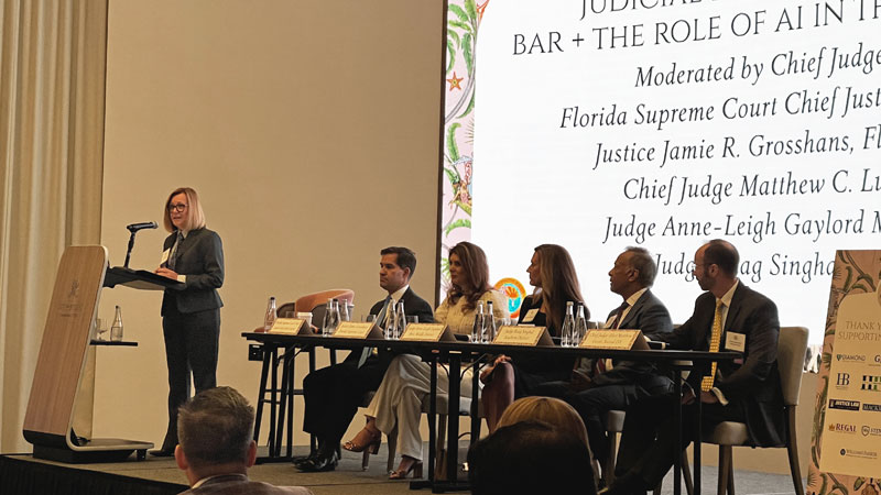 One moderator and five people sit on an elevated platform and speak to an audience.